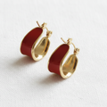 Red and gold hoop earrings on white linen